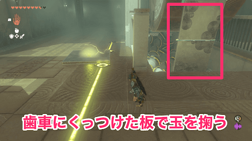 金属板を歯車にセットして玉を掬い上げる